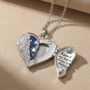 Heart-shaped locket with angel wing design and blue stones on a beige background