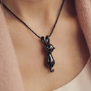 Black cat-shaped pendant on a necklace against a neutral background