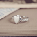 Silver heart-shaped ring with small diamonds on a textured surface