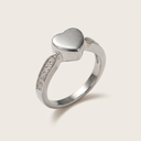 Silver ring with a heart-shaped top on a light beige background