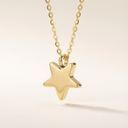 Gold star-shaped pendant on a chain against a beige background