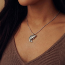 Close-up of a person wearing a silver fish pendant necklace.