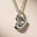 Silver heart-shaped pendant necklace on a beige background