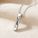 Silver necklace with a diamond pendant on a beige fabric background