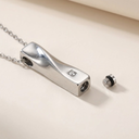 Silver pendant with a small gemstone on a beige background