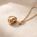 Gold necklace with a heart-shaped pendant on a beige fabric background