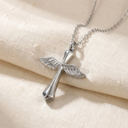 Silver cross necklace with wings on a beige fabric background